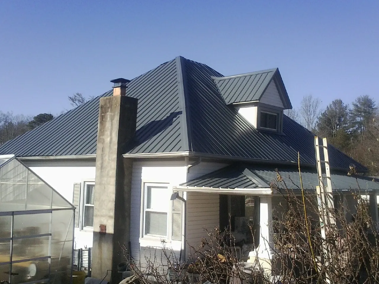 Dark blue standing seam metal roof on a white farmhouse with dormer — Slate & Tile Roof Repair by Roofing Brothers in South Chatham