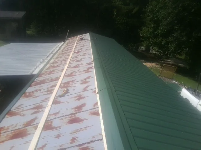 Old rusted panels beside newly installed green metal roofing — Wind Damage Roof Repair by Roofing Brothers in South Chatham