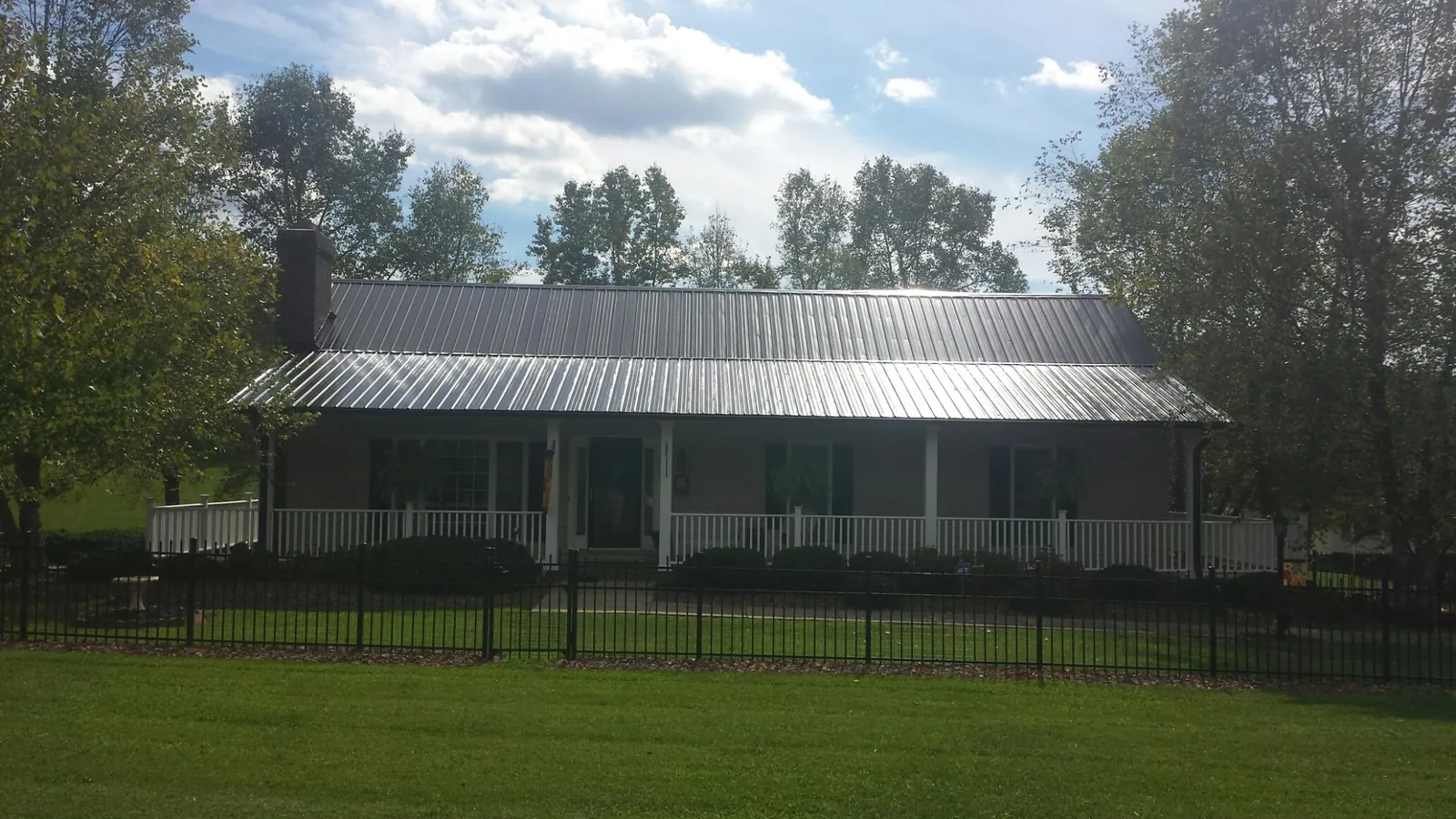 Gray metal roof on a brick ranch with a full width front porch — Gutter Guard Installation work by our crew in South Chatham