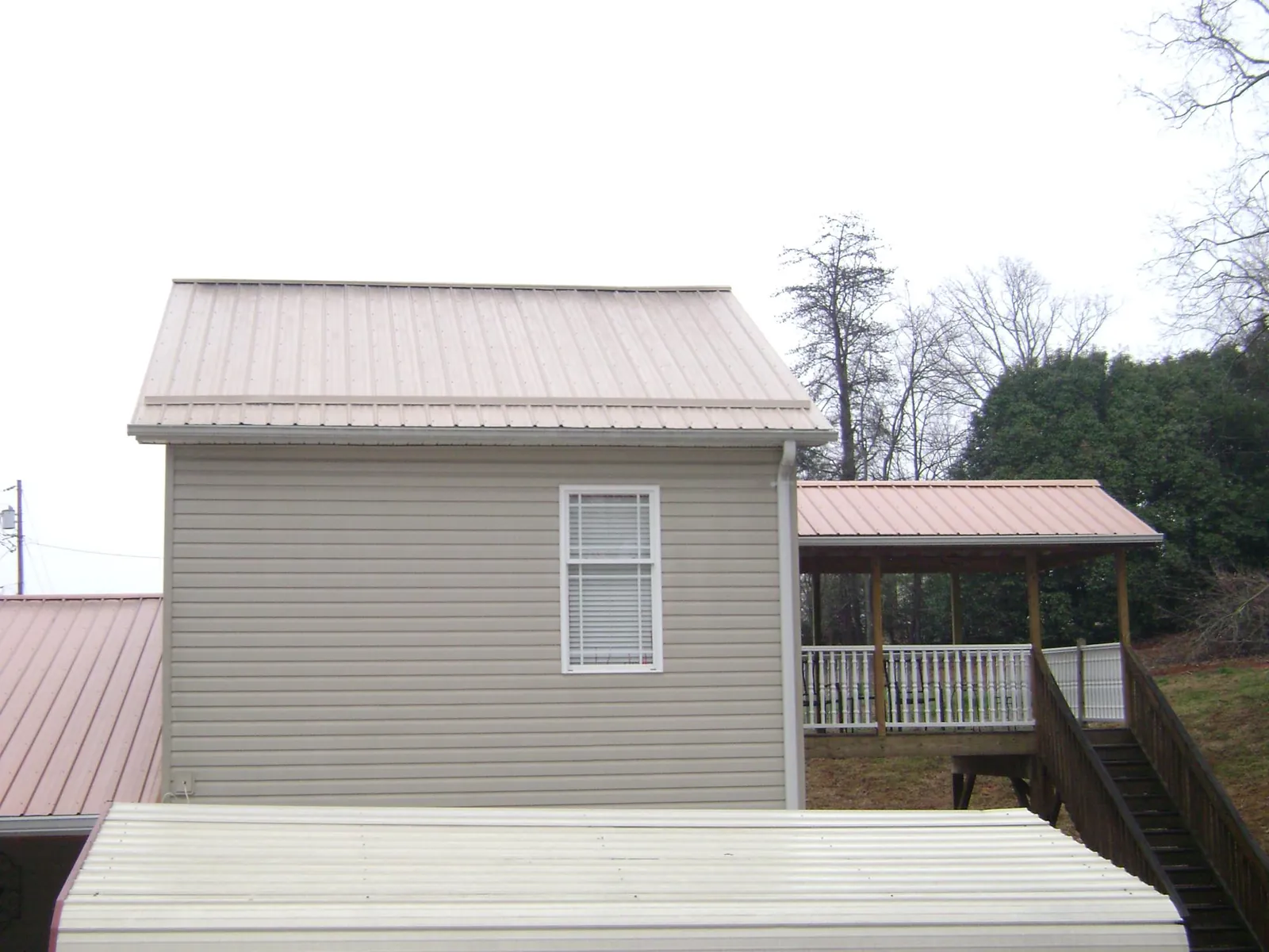 Tan metal roofs on a two story addition and attached porch, from a Roof Replacement job in South Chatham