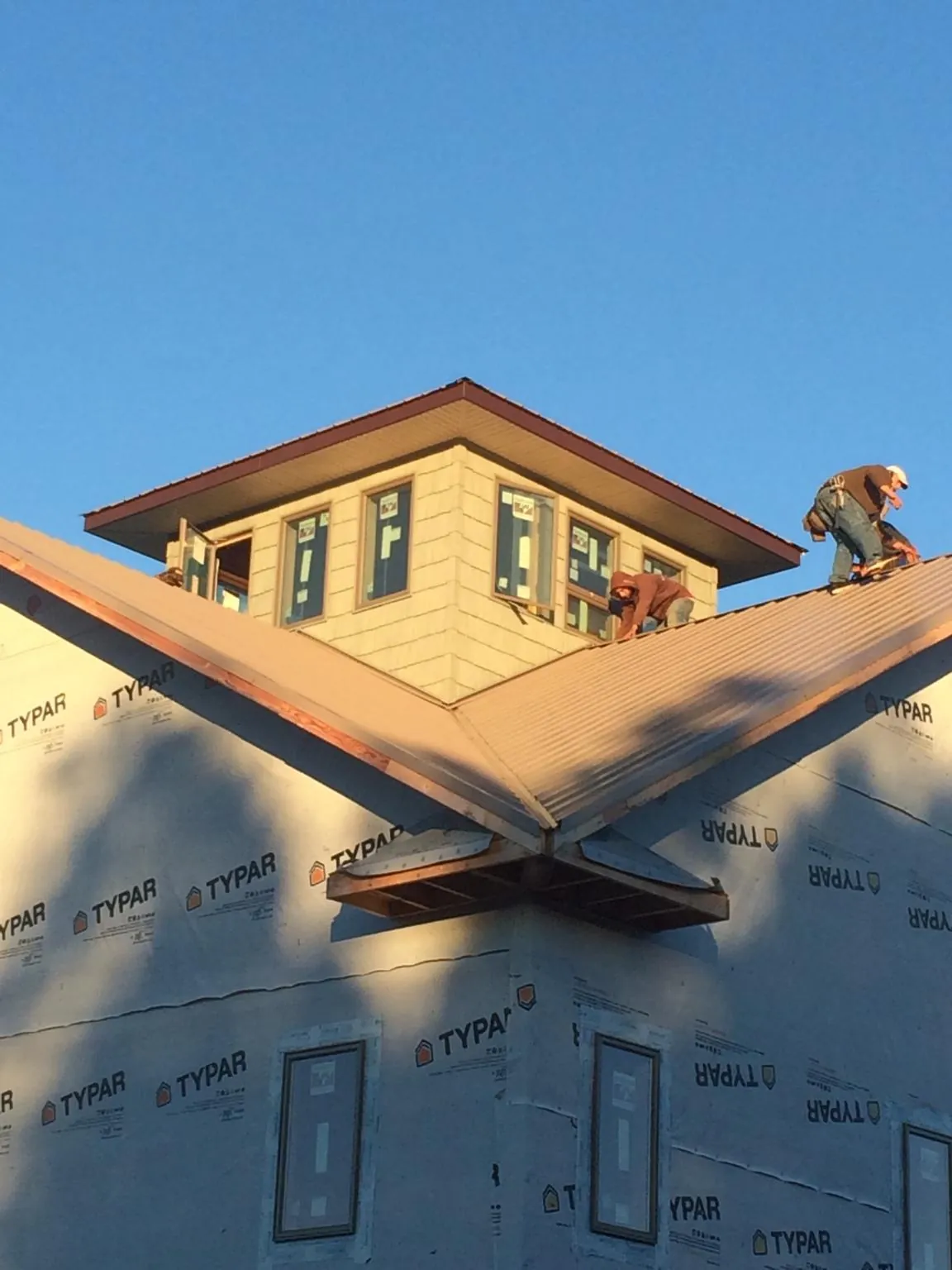 Roofers working around a rooftop cupola on a new metal roof at sunset — Roof Waterproofing in South Chatham by Roofing Brothers